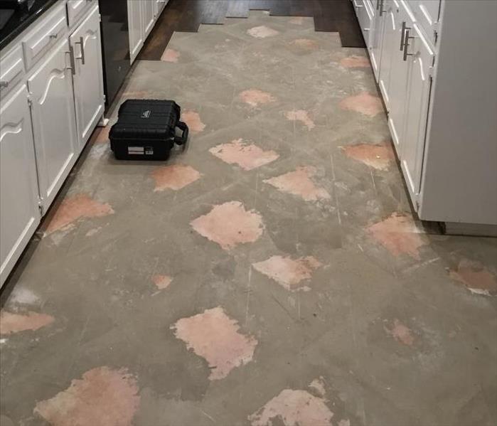 cement and tile floor in a kitchen with white cabinets
