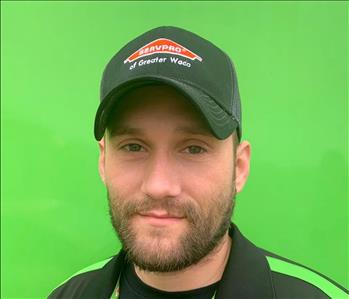 Male Crew Member Ryan in a SERVPRO black polo style shirt and SERVPRO hat