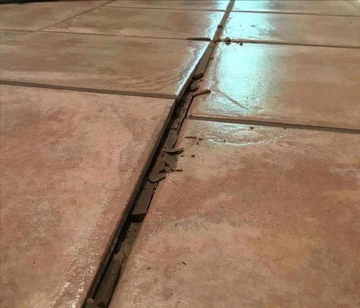 Closeup of reddish tiles where floor has buckled
